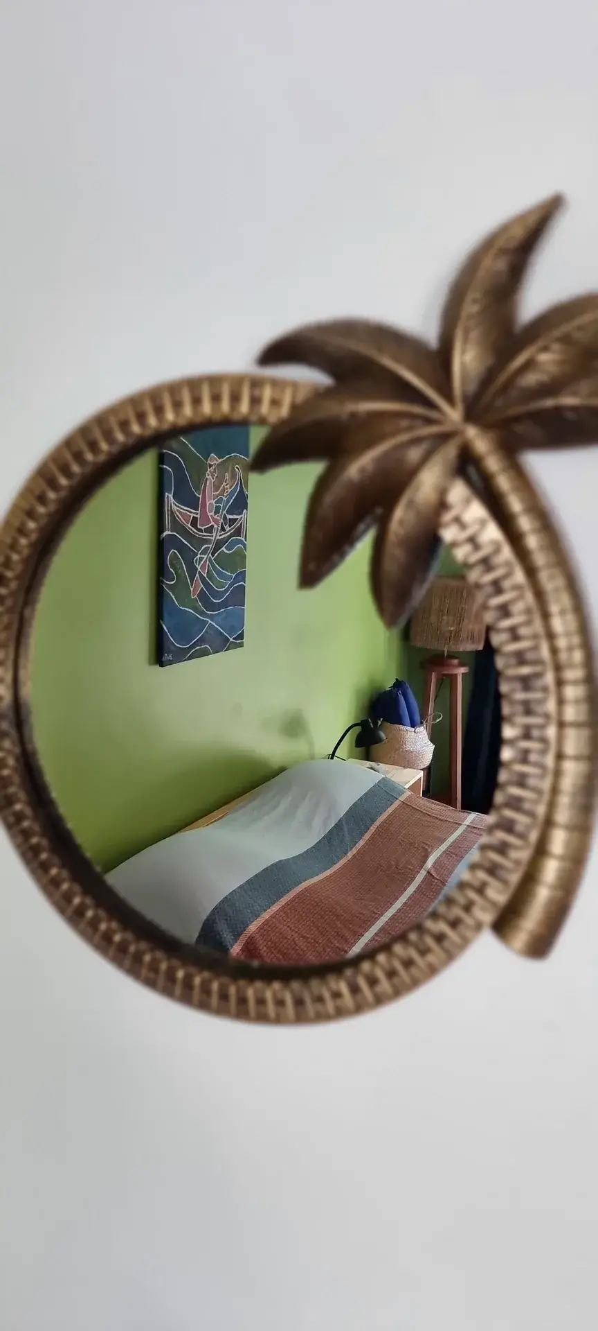 Double bed and local artwork reflected in a palm-shaped mirror in the Green Room