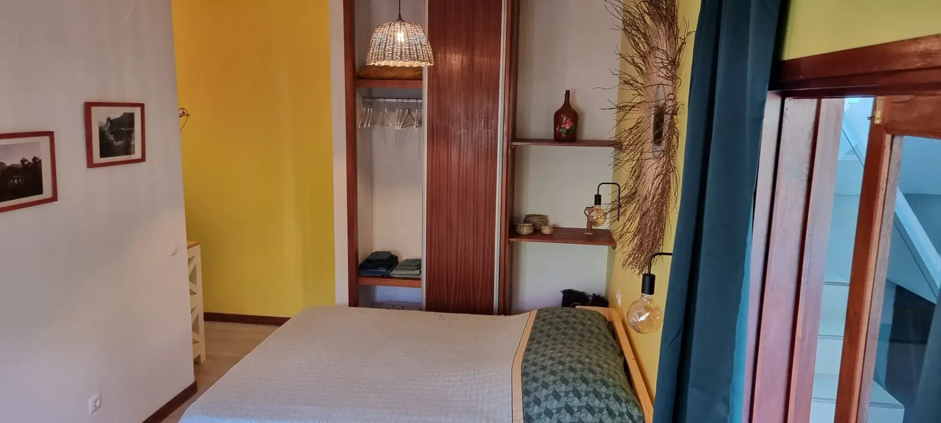 Double bed, built-in wardrobe and decorative woven mirror in the Yellow Room