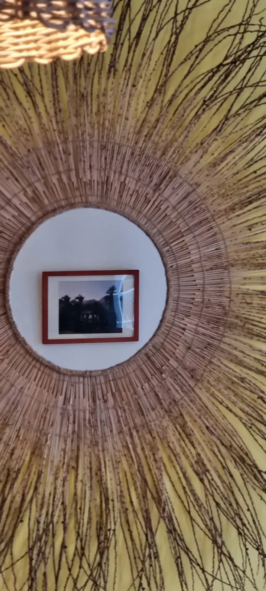 Woven sunburst mirror and framed local photograph in the Yellow Room