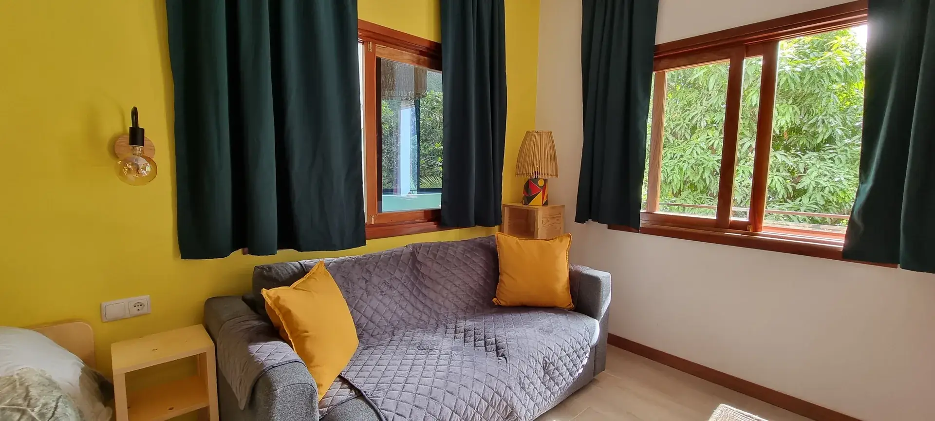 Sofa bed beside large windows overlooking the garden in the Yellow Room